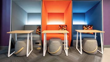 Una habitación moderna con sofá, reposapiés y una pequeña mesa, que incluye un separador con luz cálida.