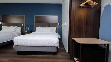 Habitación de hotel con dos camas, un escritorio, una silla y un perchero de madera.