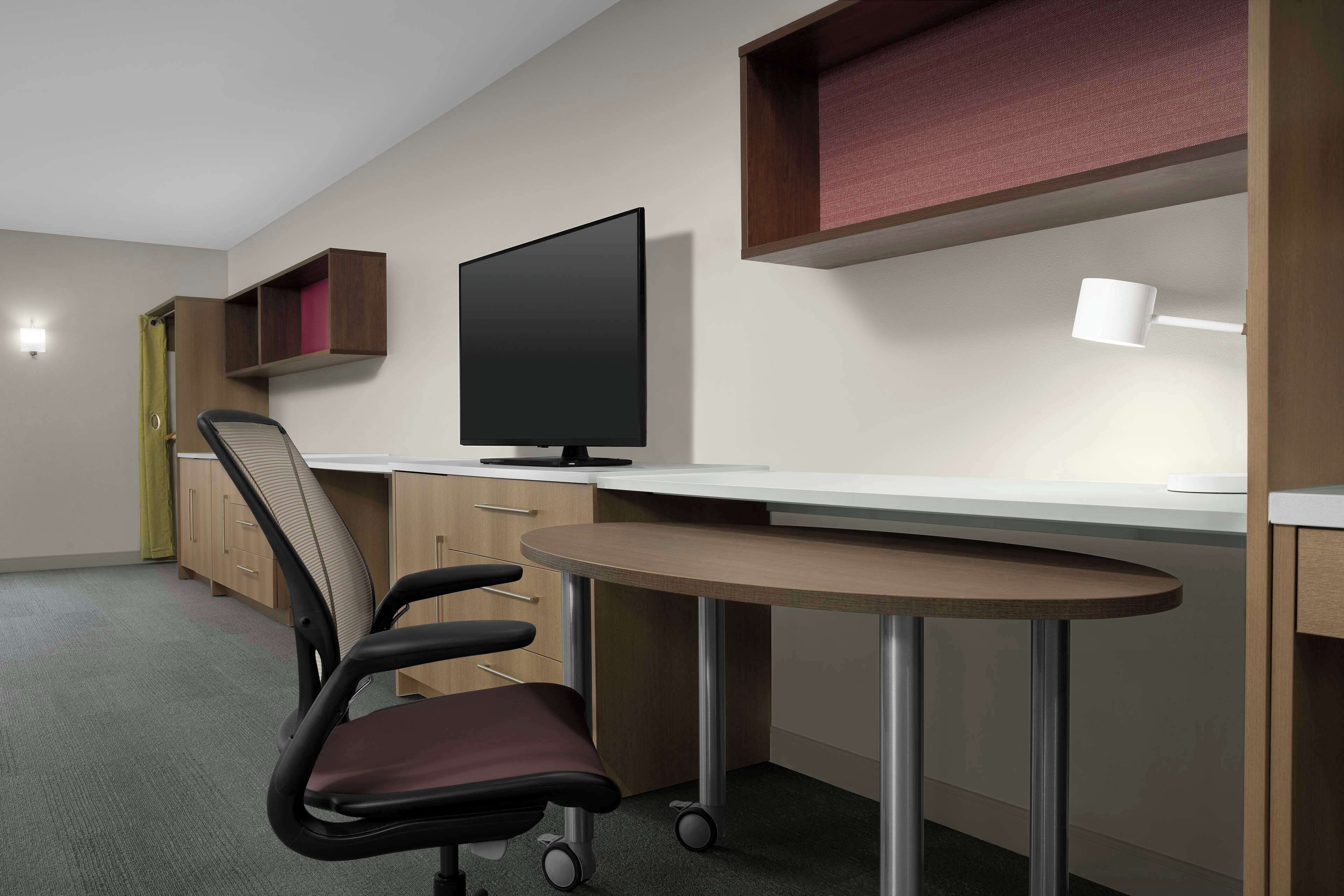 A modern office space with a desk, chair, computer, and shelving.