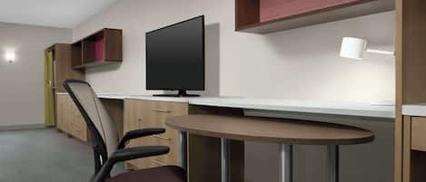 Ein moderner Arbeitsplatz mit Schreibtisch, Stuhl, Computer und Regalen.