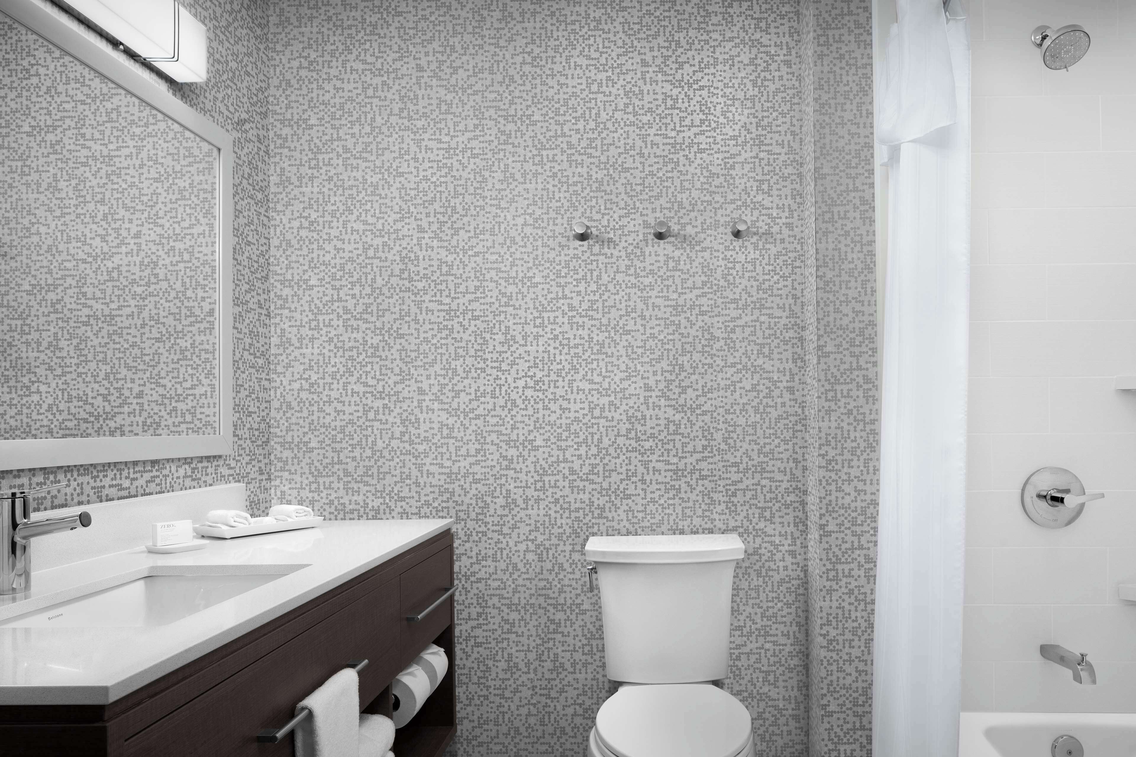 A modern bathroom with a white sink, mirror, and toilet.