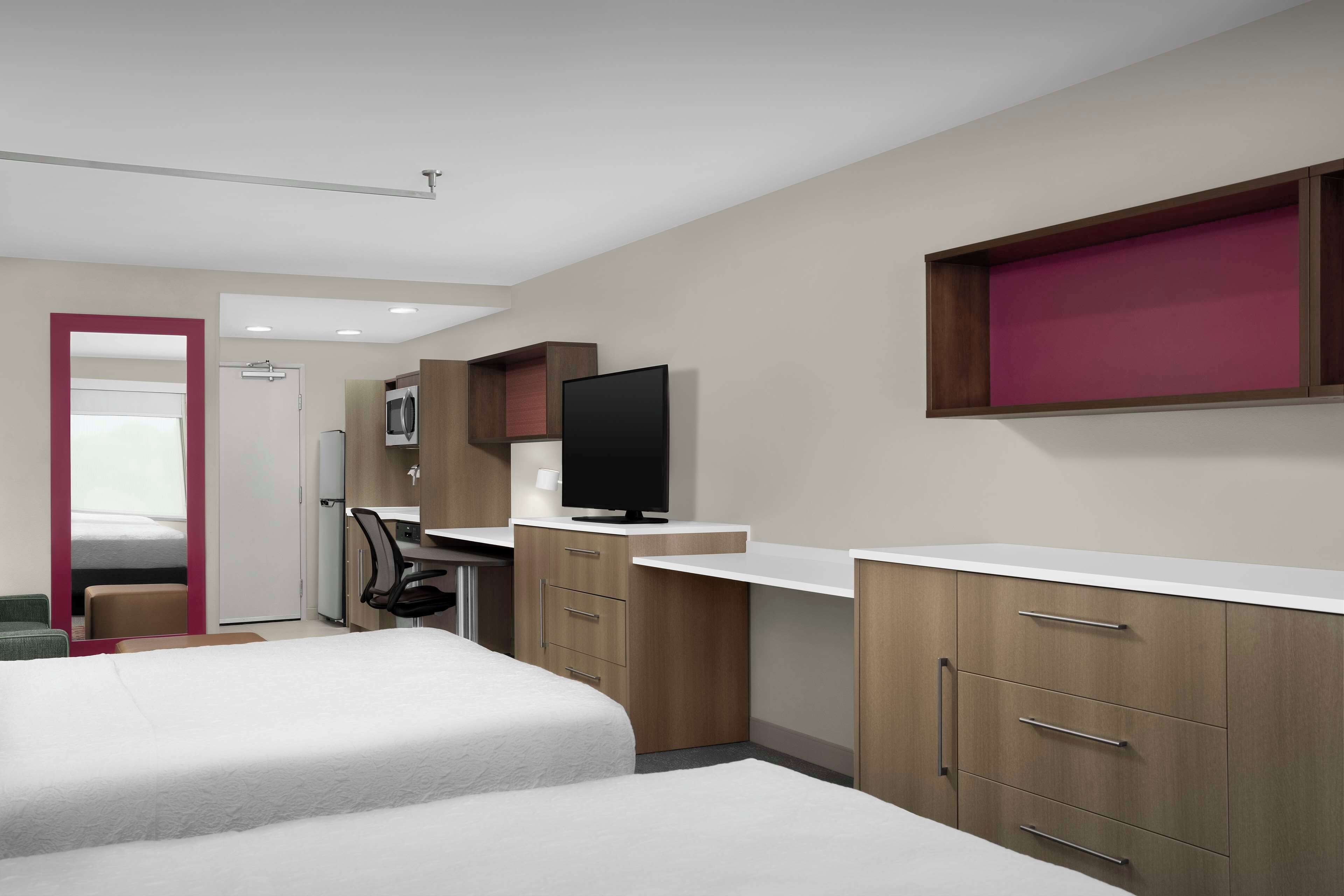 Een moderne hotelkamer met een bed, bureau, televisie en garderobe.