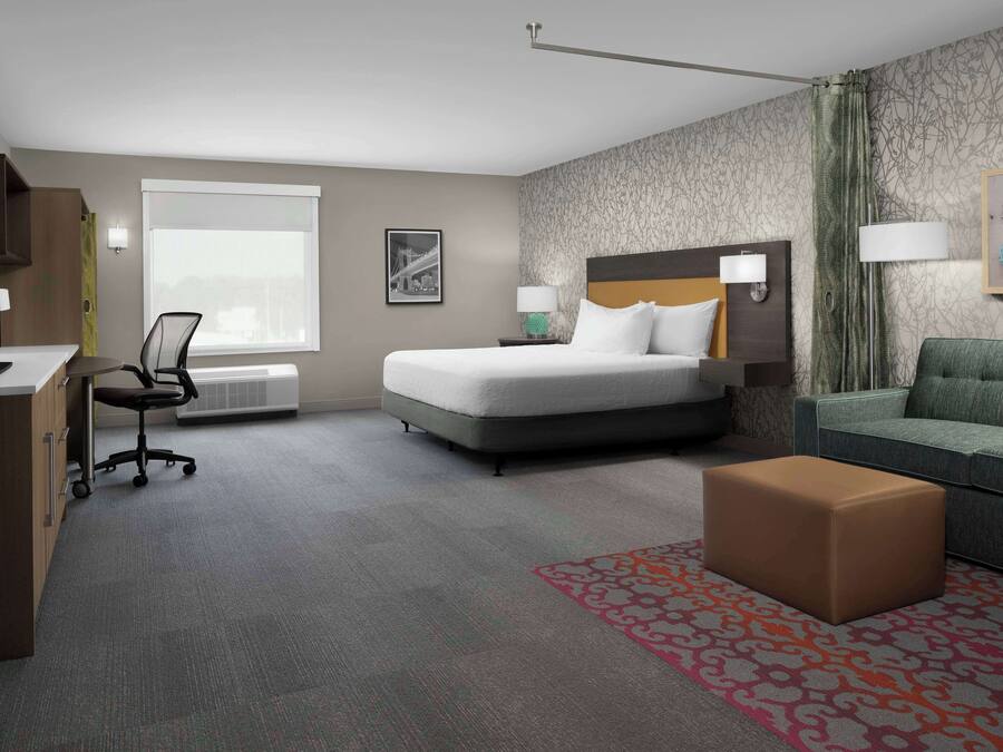 Habitación de hotel con cama, escritorio, silla, sofá y alfombra estampada.