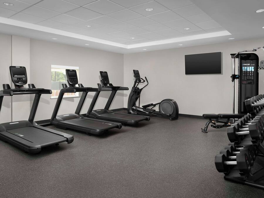 Ein Fitnessraum mit Laufbändern, einem Ergometer und Kurzhanteln.