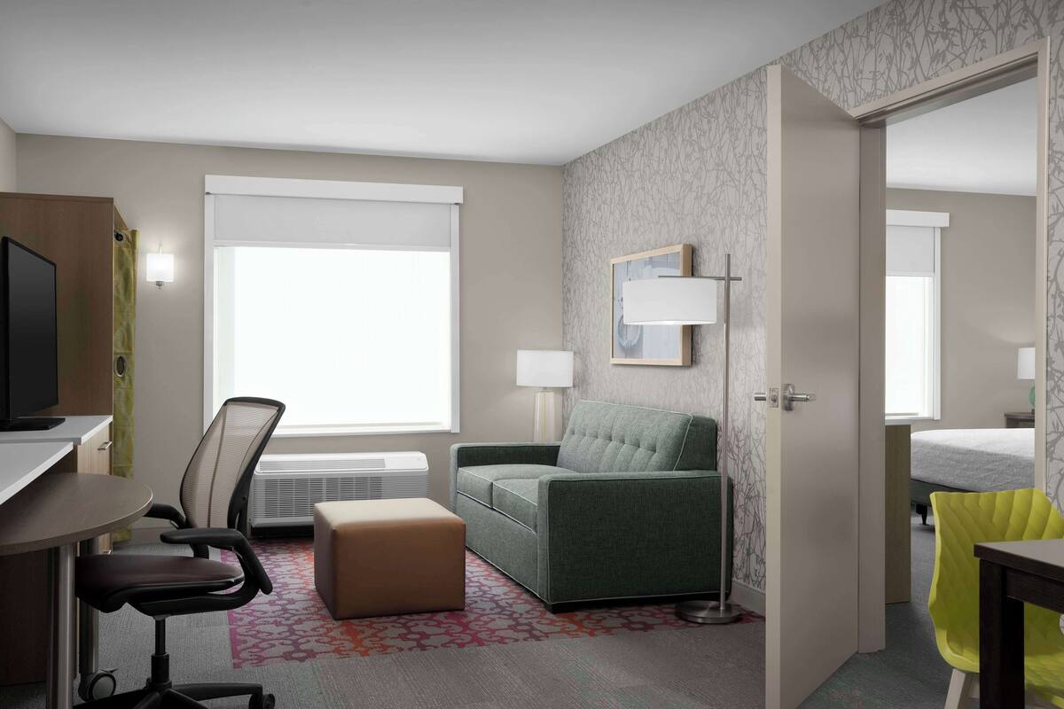 A hotel room with a desk, office chair, sofa, and a bed.