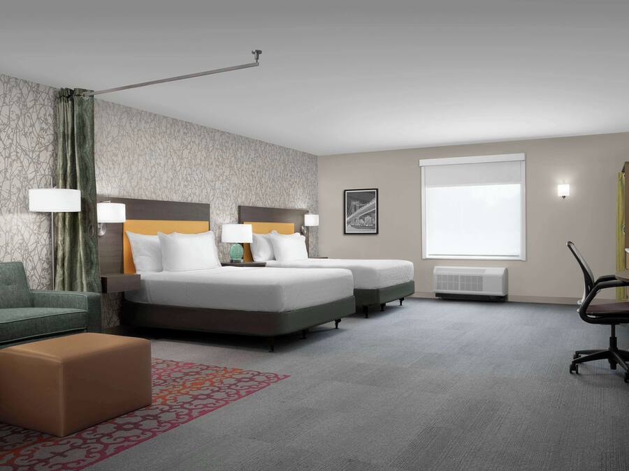 A hotel room with two single beds, a sofa, a desk, and a chair.
