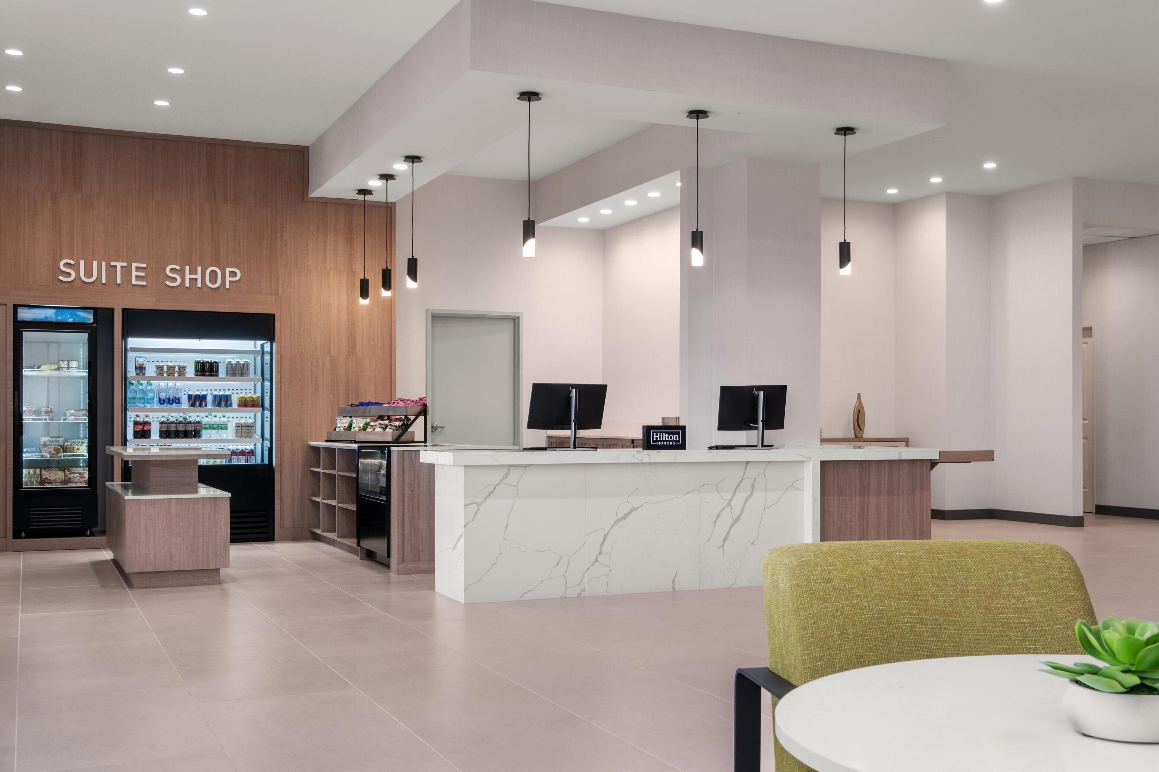 Ein Hotel-Rezeptionsbereich mit Marmor-Theke, einer Minibar und einem Schild mit der Aufschrift 'Suite Shop'.