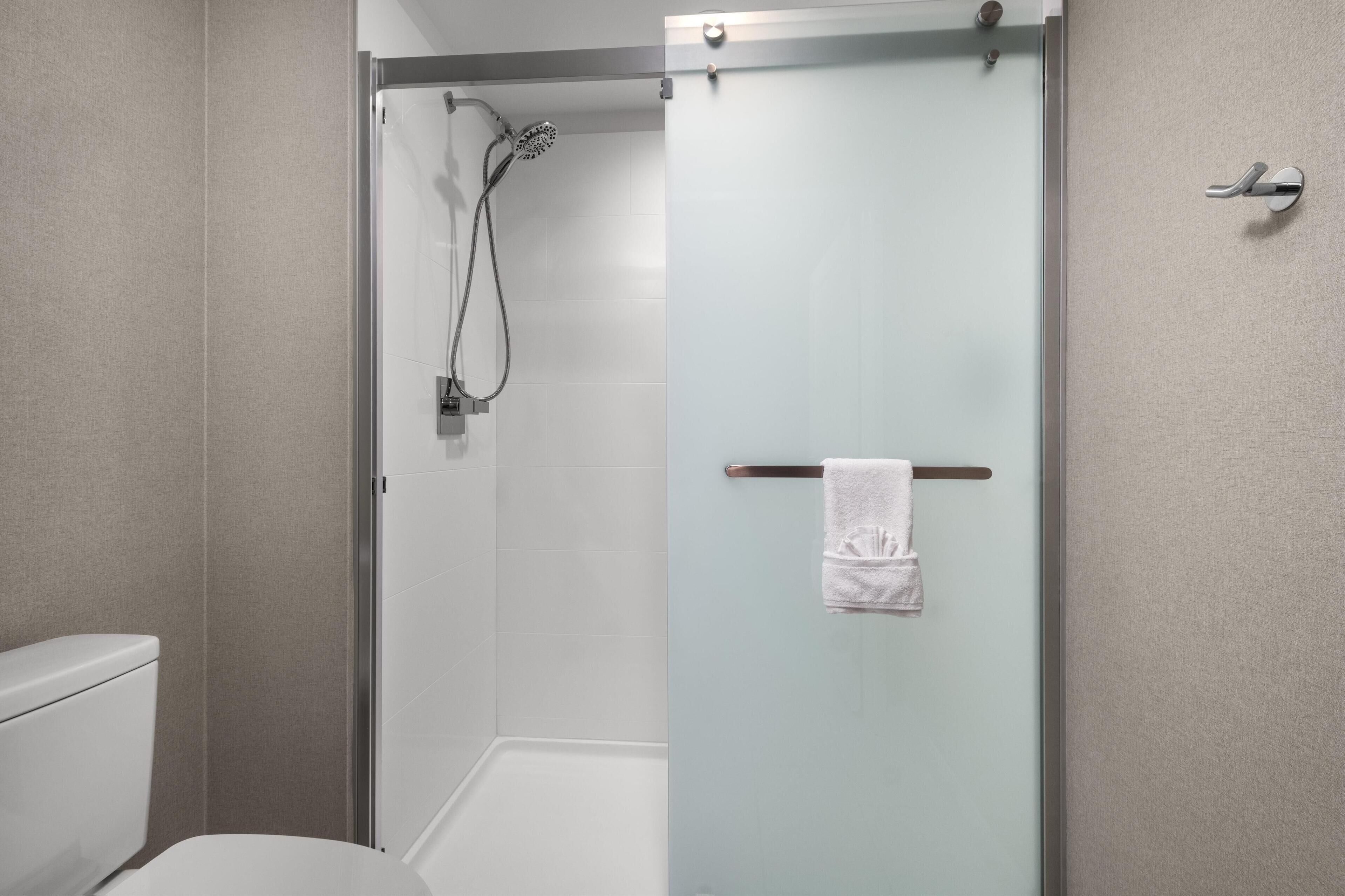 A modern bathroom with a glass shower enclosure, a toilet, and a towel rack with a towel.