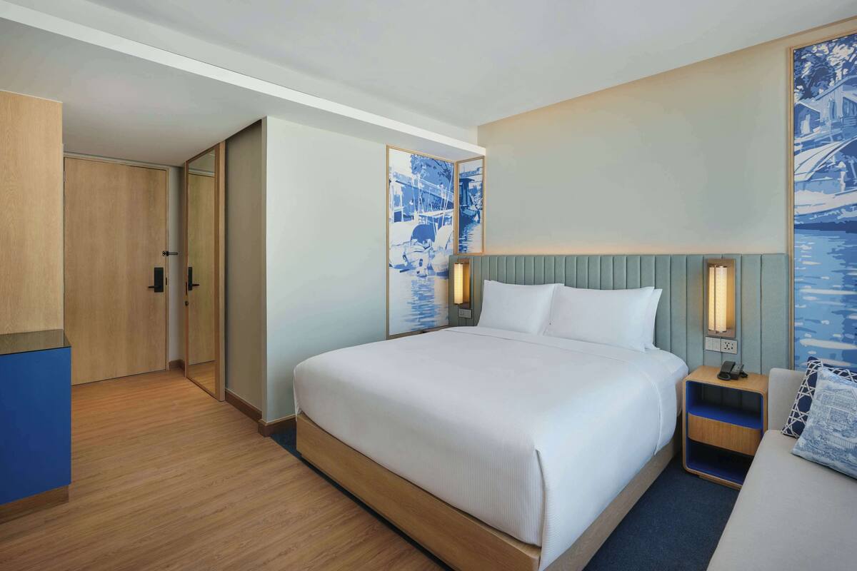 A hotel room with a large bed, bedside tables, a wardrobe, and artwork on the walls.