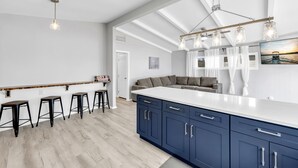 A modern kitchen with a large island, bar stools, and a hanging light fixture. - The Blue Haven Getaway in cozy Kingsland, TX (Kingsland)