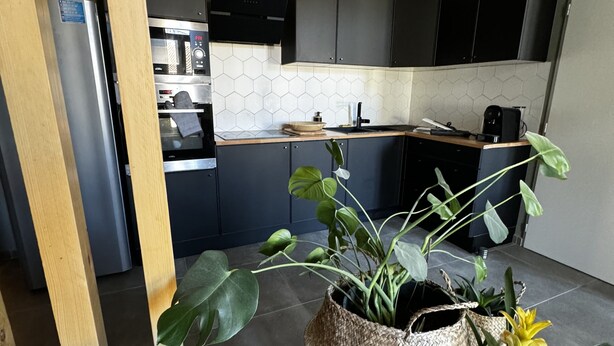 A modern kitchen with dark cabinets, a microwave, and a hanging light fixture. - Les Copains D'abord (Nîmes)