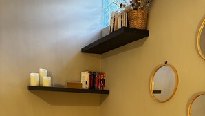 A corner of a room with a woven chair, a small table with candles, a bookshelf, and two wall-mounted mirrors. - Les Copains D'abord (Nîmes)