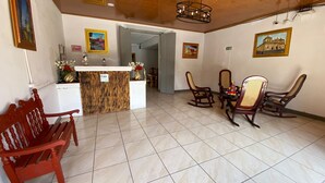 A reception area with a wooden reception desk, a red bench, and several rocking chairs. - Hostal Pochote  (León)