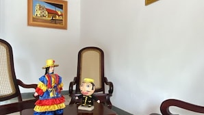 A room with two wooden chairs, a small table, and a painting on the wall. - Hostal Pochote  (León)