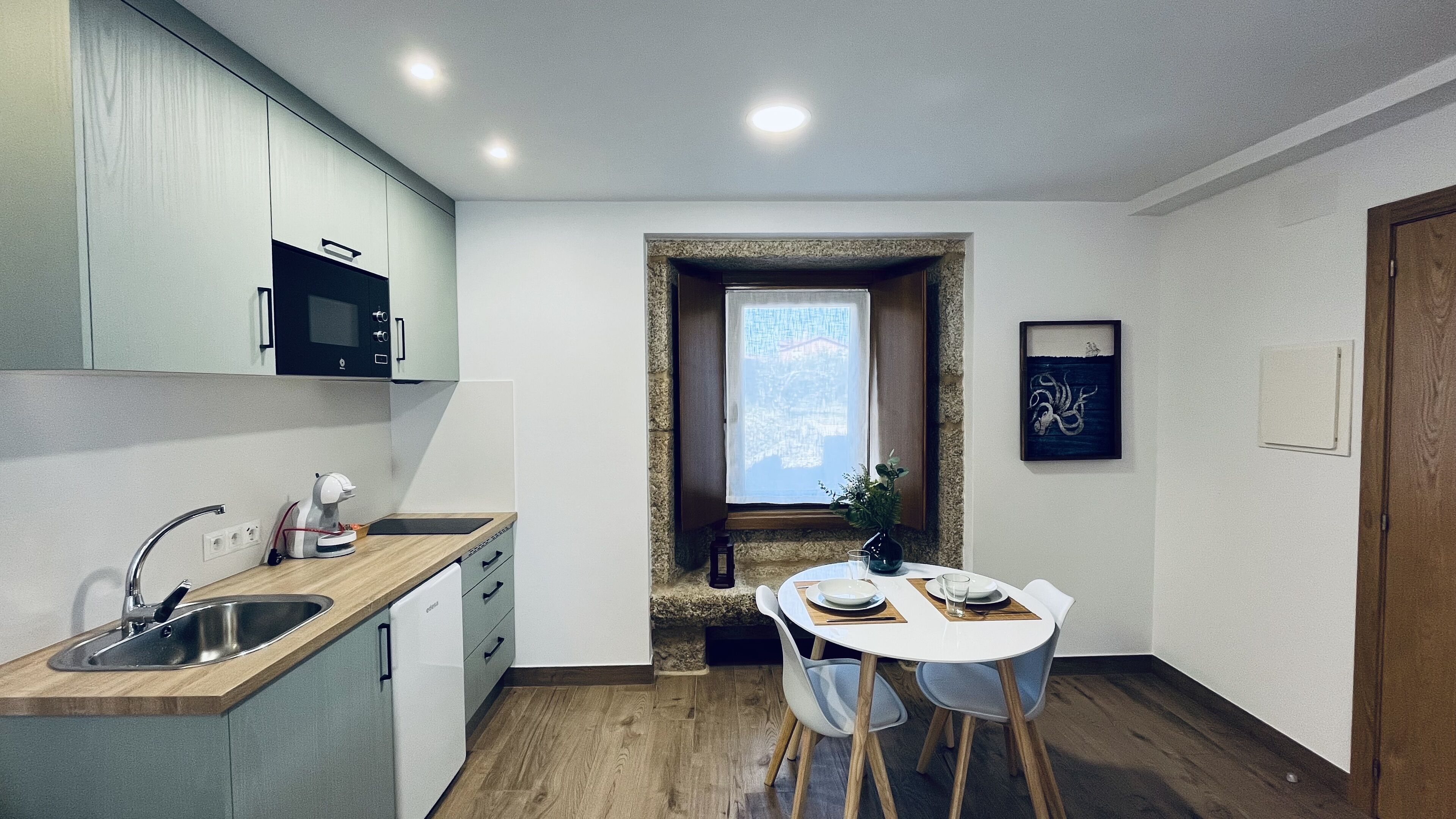 A compact kitchen with a built-in microwave, a sink, and a dining area with a table and chairs.