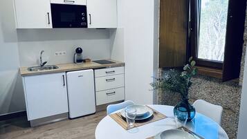 Una cocina moderna con armarios blancos, horno empotrado y ventana con vistas a árboles.