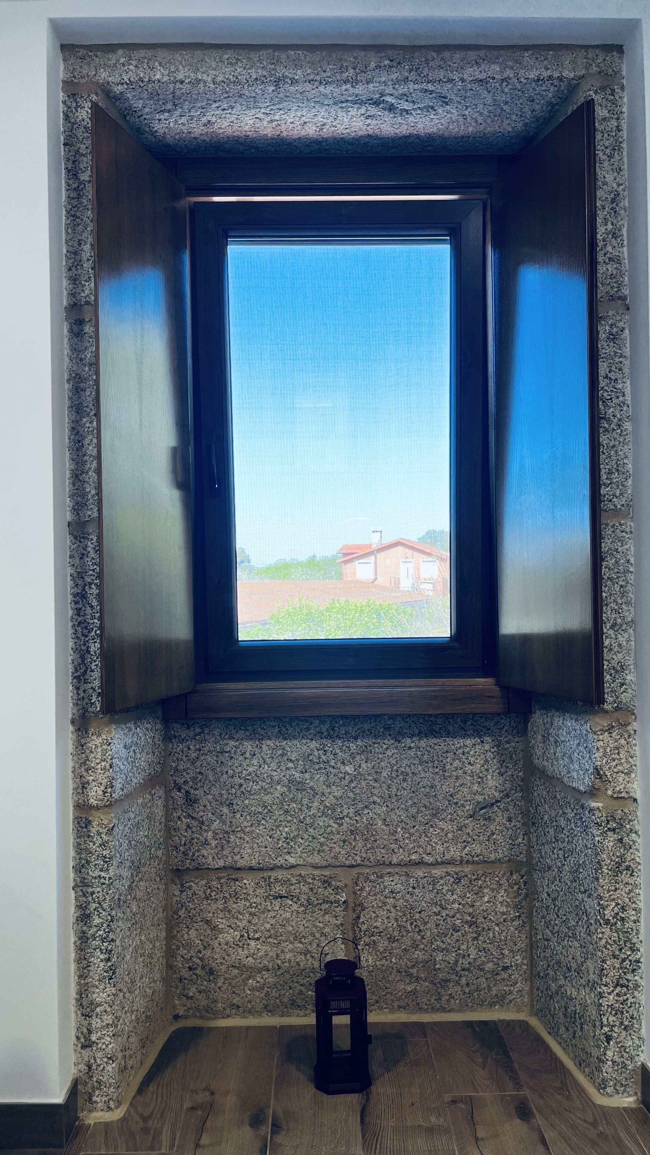A small window with a view of a building and a field.