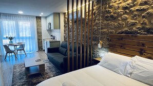 Una habitación de hotel moderna con cama, sofá, mesa de comedor y zona de cocina.