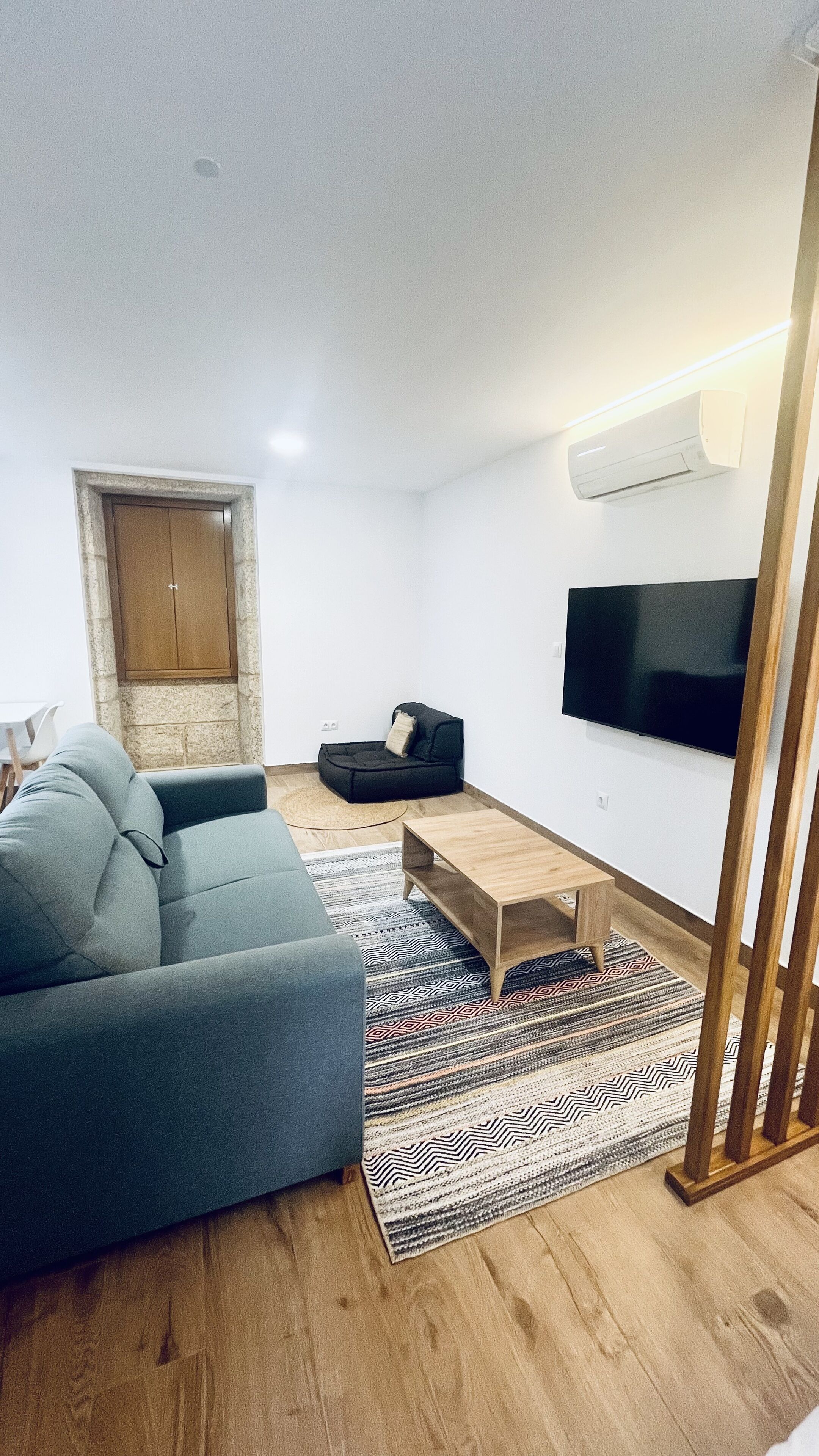 A modern living room with a grey sofa, a wooden coffee table, and a patterned rug.