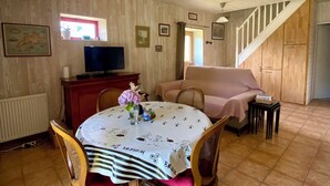 A dining area with a round table, chairs, and a ceiling light fixture. - In the countryside, beaches just a few minutes away... (Plomeur)