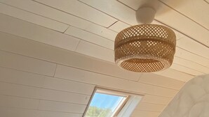 A bedroom with a sloped ceiling, a skylight, a bed with a floral bedspread, and a woven light fixture. - In the countryside, beaches just a few minutes away... (Plomeur)