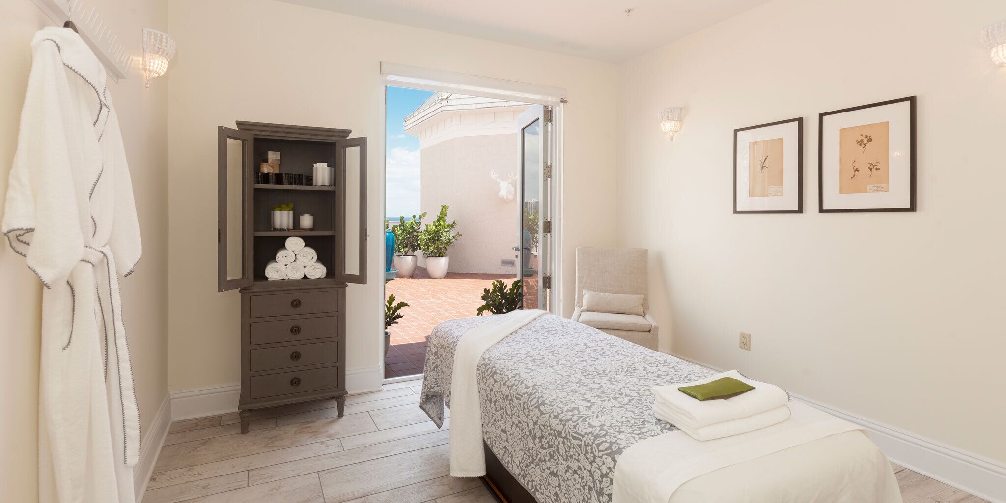 Ein Schlafzimmer mit Bett, Stuhl, Kleiderschrank und einer Tür zu einem Außenbereich mit Pflanzen.
