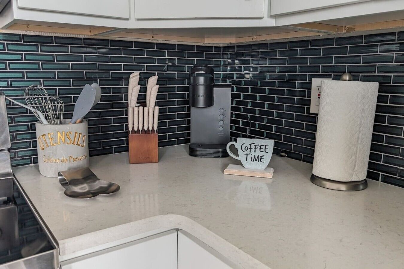 A kitchen counter with a coffee maker, a sign that says 'Coffee Time,' a knife block, and a utensil holder.