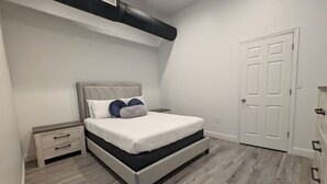 Une chambre à coucher avec un lit, des tables de chevet, une commode et une porte.