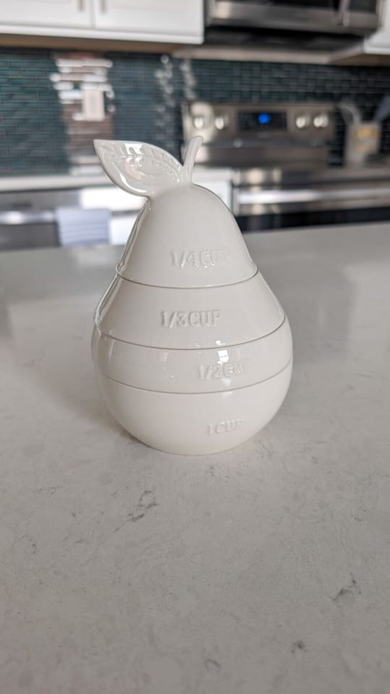 Un verre doseur blanc, gradué, posé sur un plan de travail de cuisine.