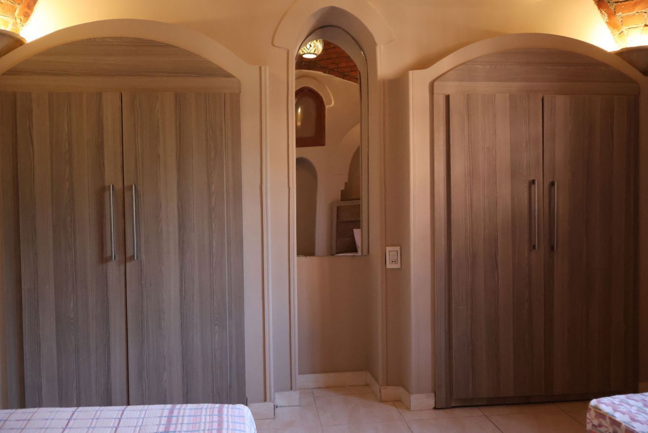 A bedroom with two wardrobes, a bed, and a staircase leading to an upper level.