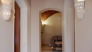 Un pasillo con una puerta de madera, un banco y una pared de ladrillo.