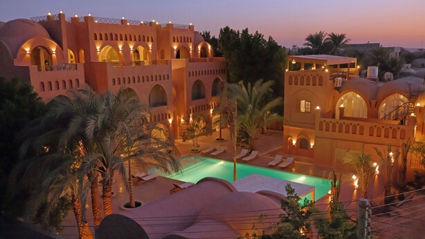 A resort with a swimming pool, palm trees, and traditional architecture. - Malkata House - 32 ppl - Desert Oasis: Pool & Dine (Luxor)