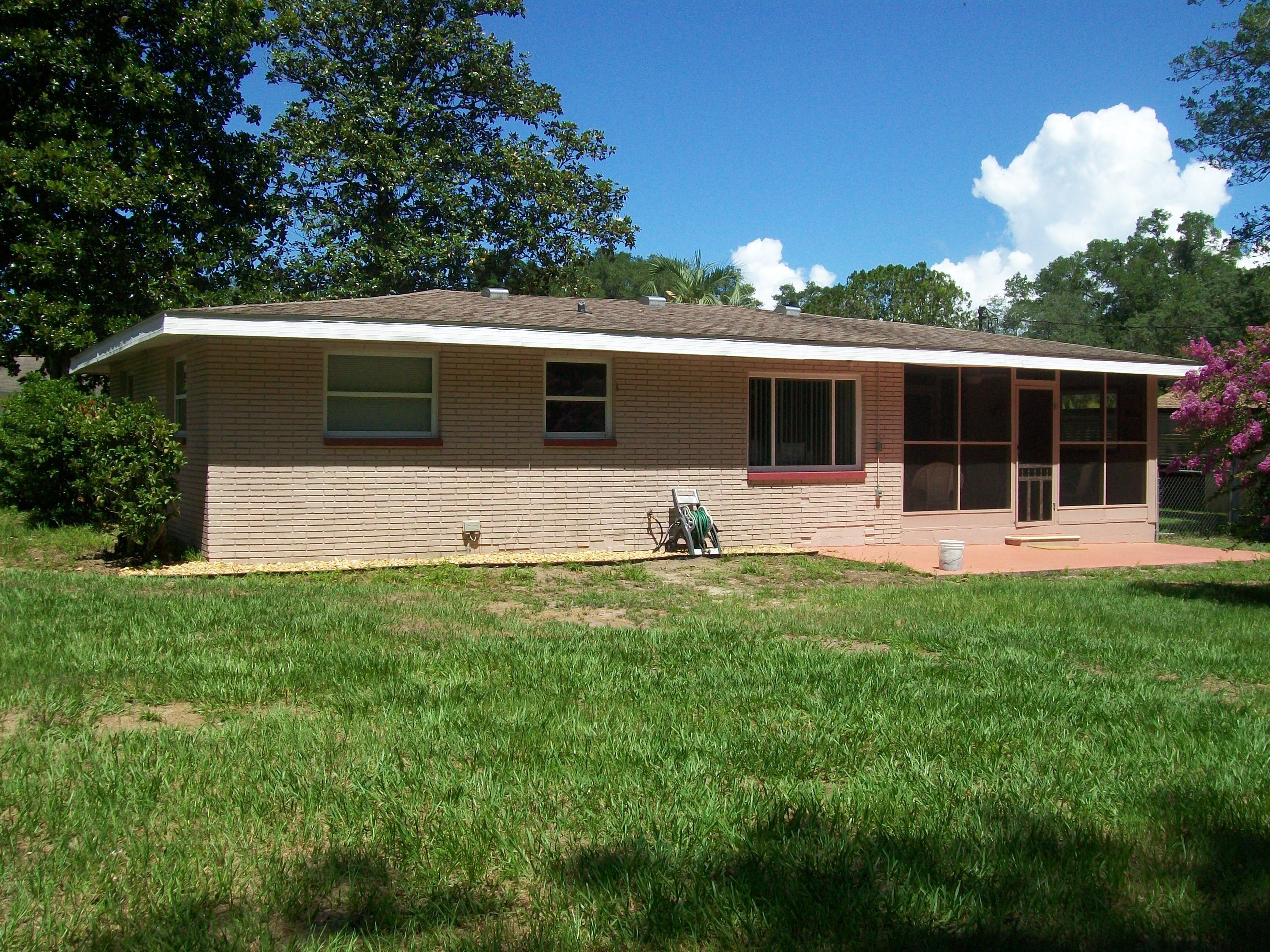 A single-story house with a brick exterior, a front porch, and a covered patio area.