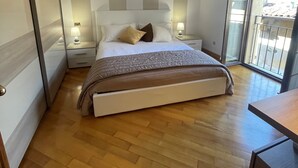 Een slaapkamer met een bed, nachtkastjes, een lamp en uitzicht door een schuifdeur.