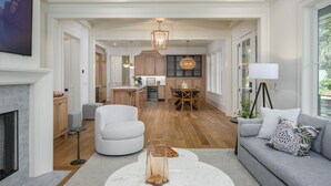 A spacious living area with a fireplace, a sofa, a coffee table, and a dining area with wooden furniture. - Gorgeous new luxury beach house - be the first to experience this dream home! (Hilton Head)