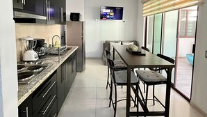 A modern kitchen with dark cabinets, a built-in stove, and a dining area with a table and chairs.