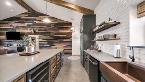 Een moderne keuken met houten details, een inbouwoven en een groot keukenblok met een spoelbak.