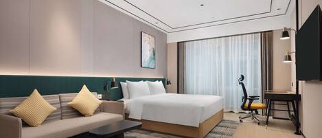 Quarto de hotel moderno com cama, sofá, escrivaninha e uma janela grande com cortinas.