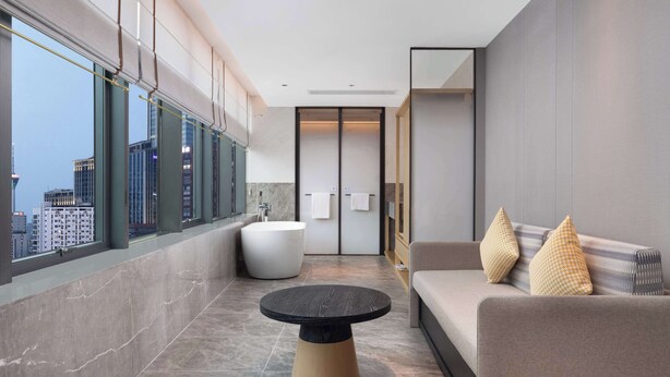 Un baño moderno con bañera, una mesita redonda y un sofá con cojines.