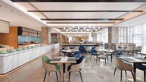 Un restaurante moderno con barra central, mostradores de mármol y varias zonas de estar.