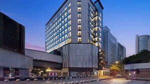 Un hotel moderno con un edificio de esquina destacado, ventanas amplias y un área de entrada bien iluminada.