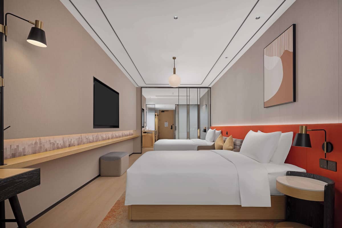 Une chambre d’hôtel avec un grand lit, un bureau, une chaise, une télévision et un tableau au mur.