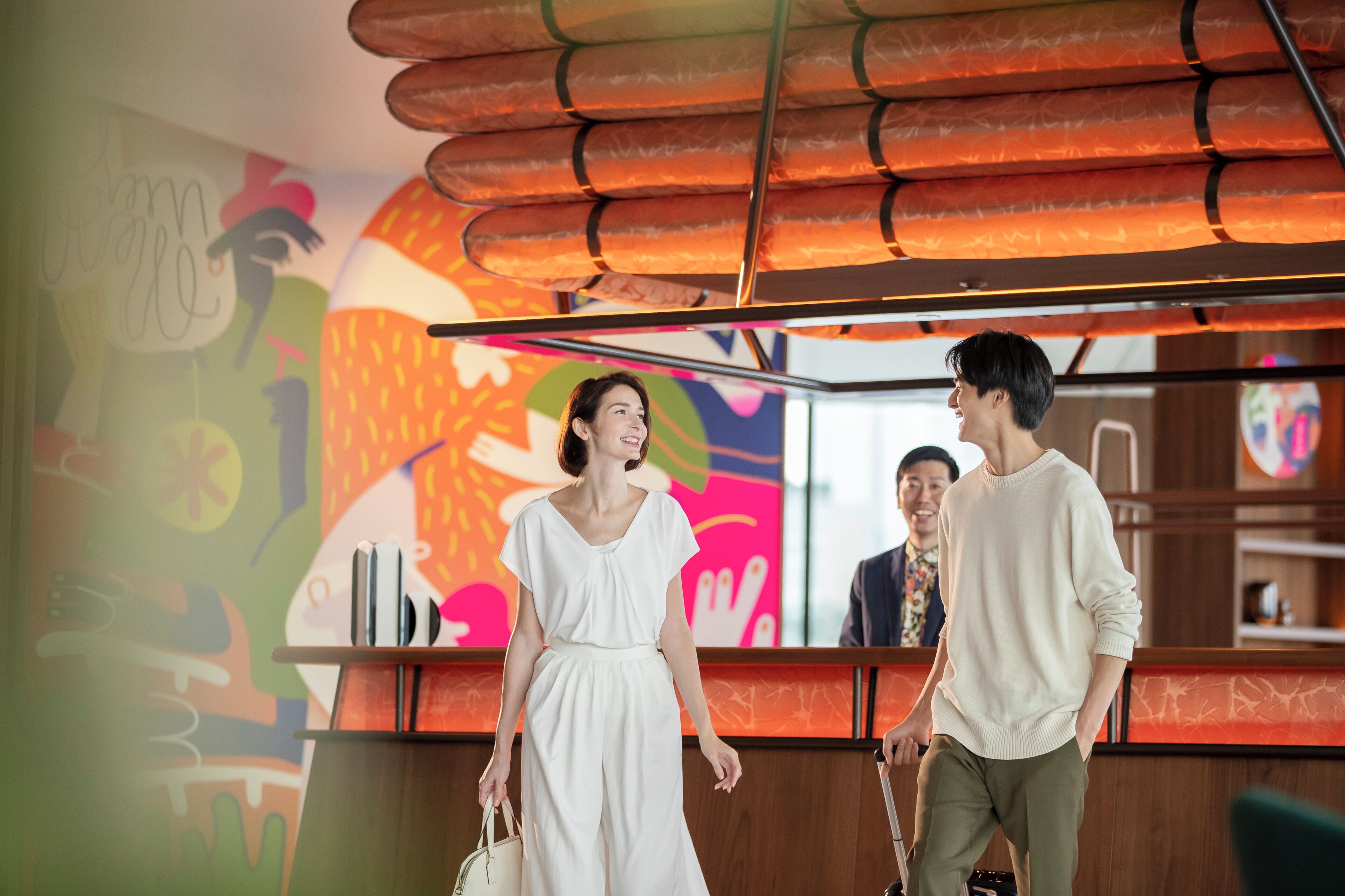 A reception area with a colorful mural, a reception desk, and a modern ceiling design.