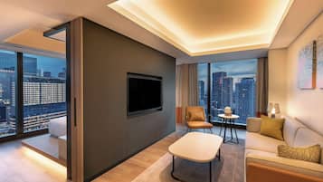 Una sala de estar moderna con un televisor de pantalla plana montado en la pared, un sofá, una mesa de centro y un sillón.