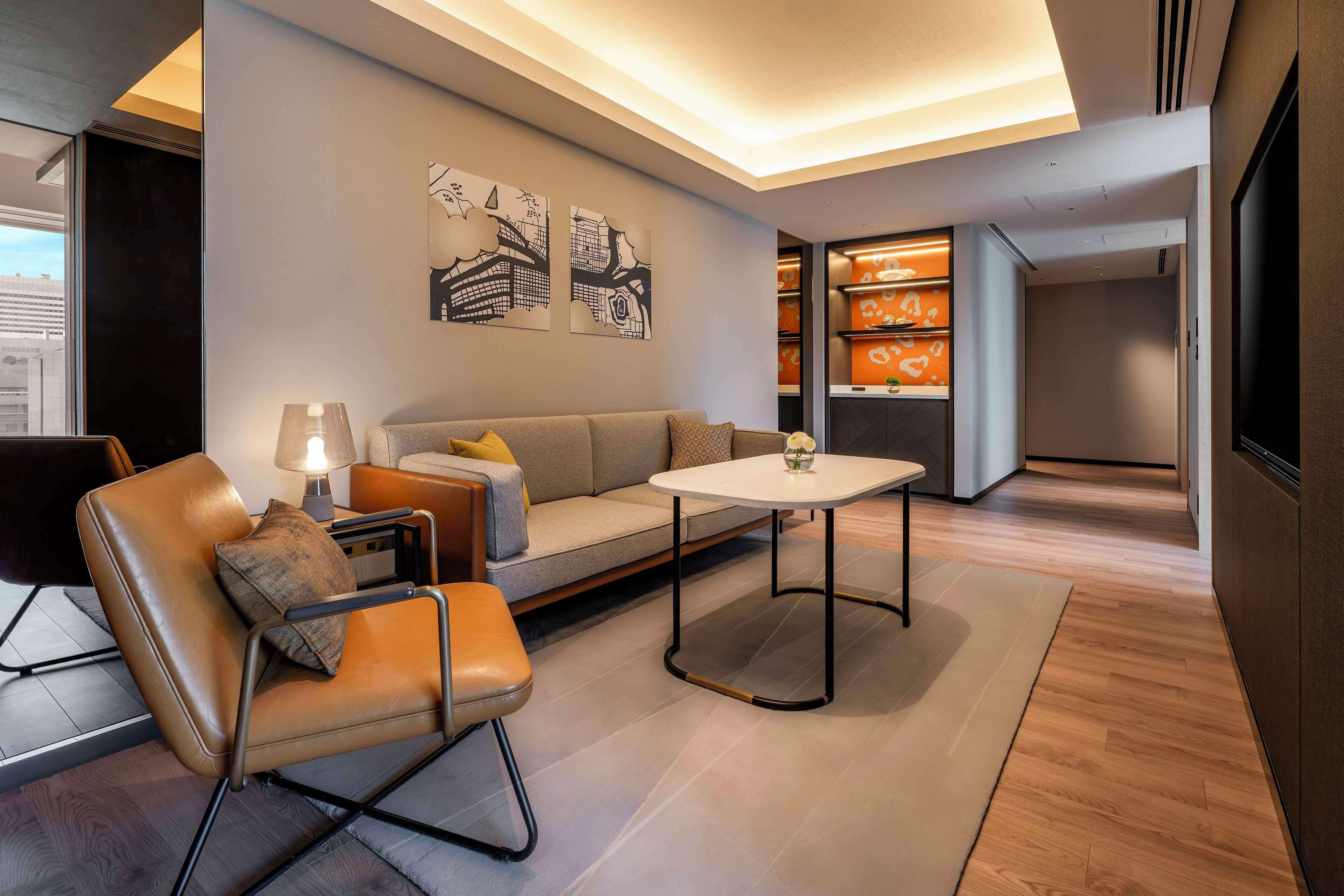 A modern living room with a sofa, a chair, a small table, and artwork on the wall.