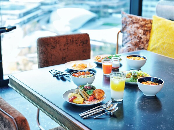 A dining table with various dishes, including a croissant, salad, and a glass of orange juice. - Canopy By Hilton Osaka Umeda (Osaka)