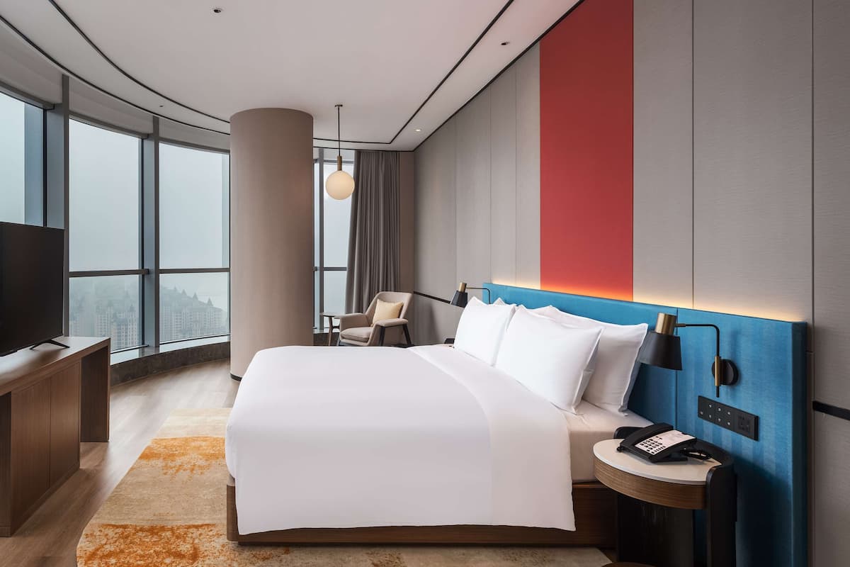 Une chambre d’hôtel moderne équipée d’un grand lit, d’un bureau, d’une chaise et d’un téléviseur.