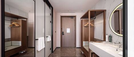 Un baño de hotel moderno con piso de mármol, armarios de madera y un espejo grande.