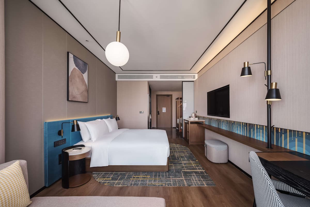 Une chambre d’hôtel moderne équipée d’un grand lit, d’un bureau, d’une télévision et d’un coin salon.