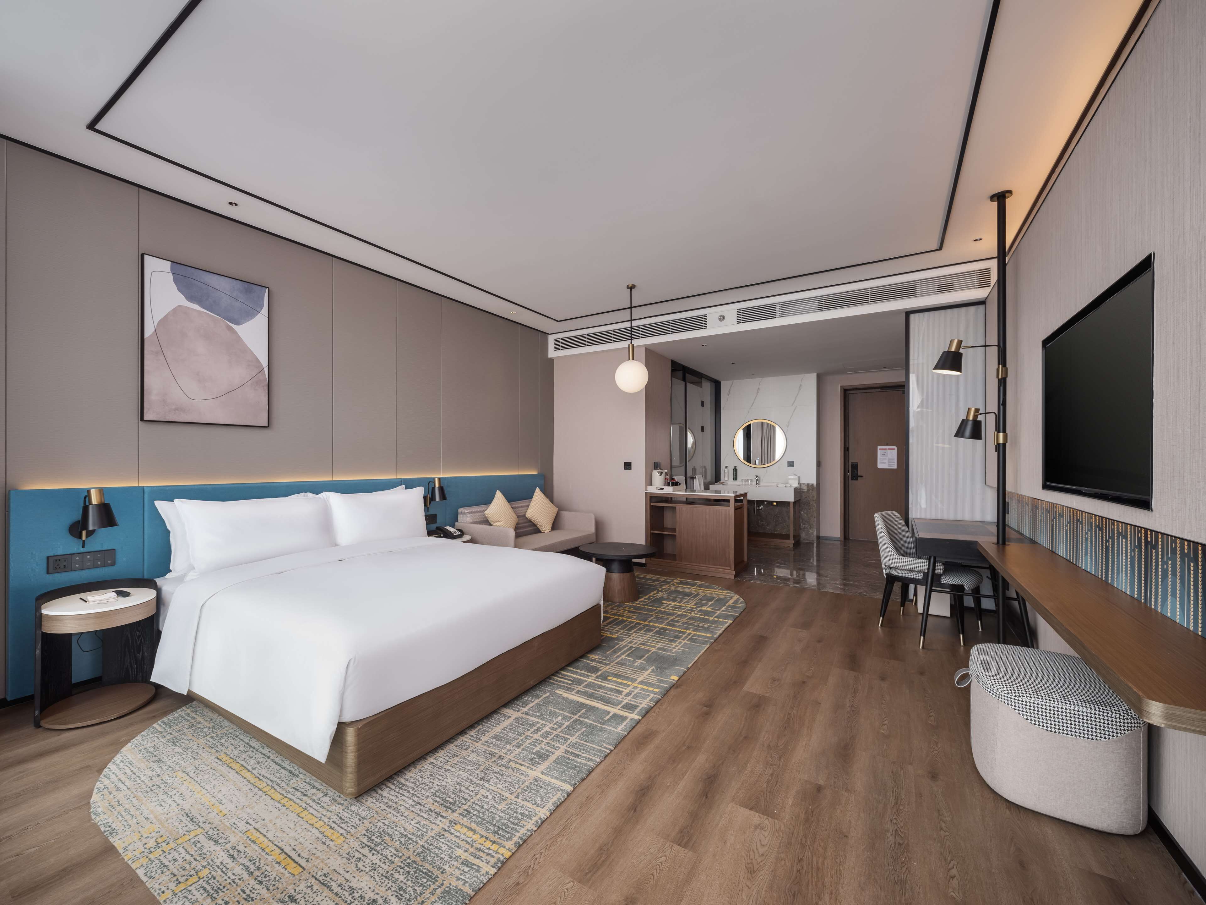 Une chambre d’hôtel moderne équipée d’un grand lit, d’un bureau, d’une chaise, d’une télévision et d’une salle de bain.
